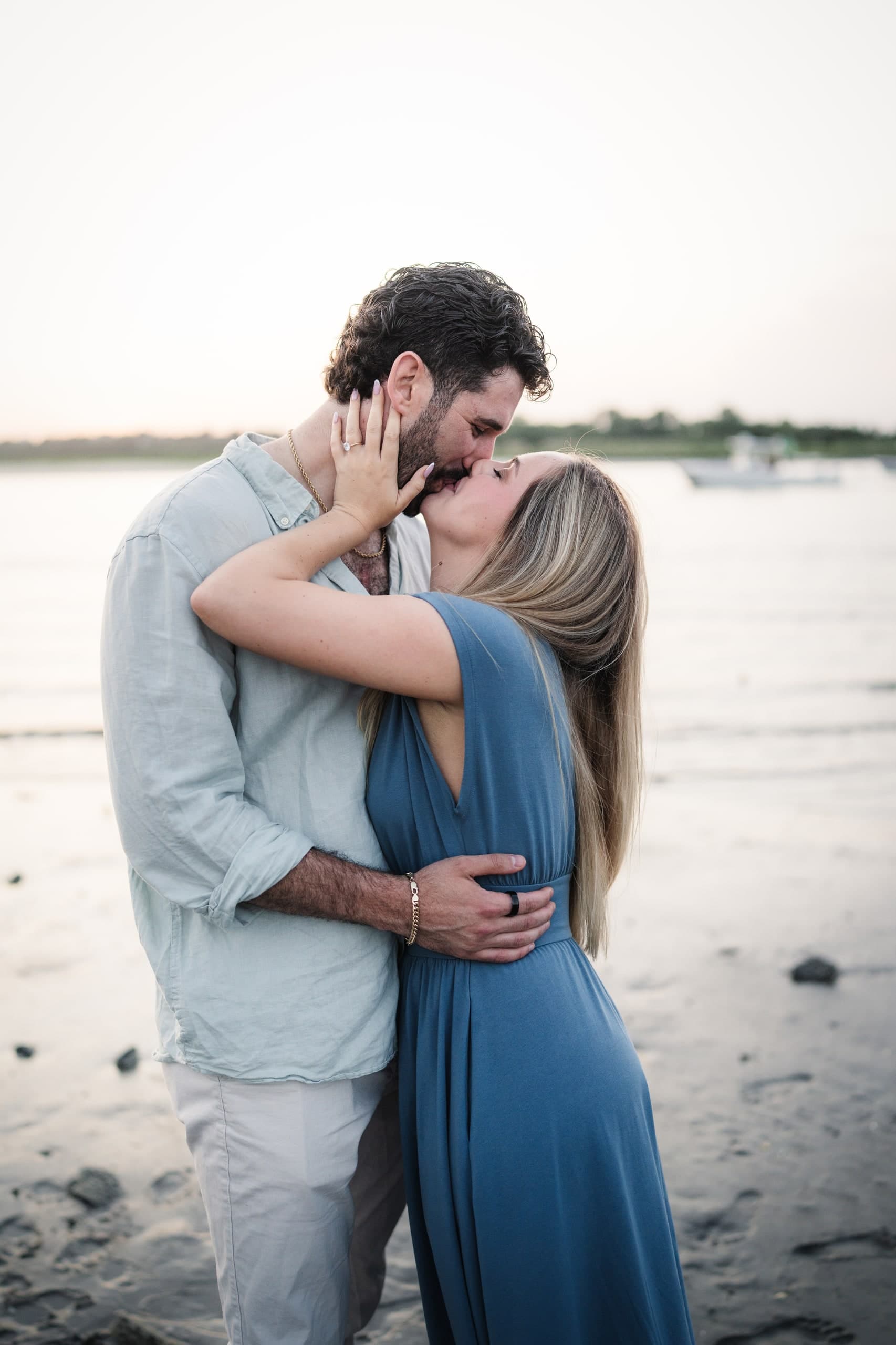 A close, tender kiss between the newly engaged couple, her hand on his face.