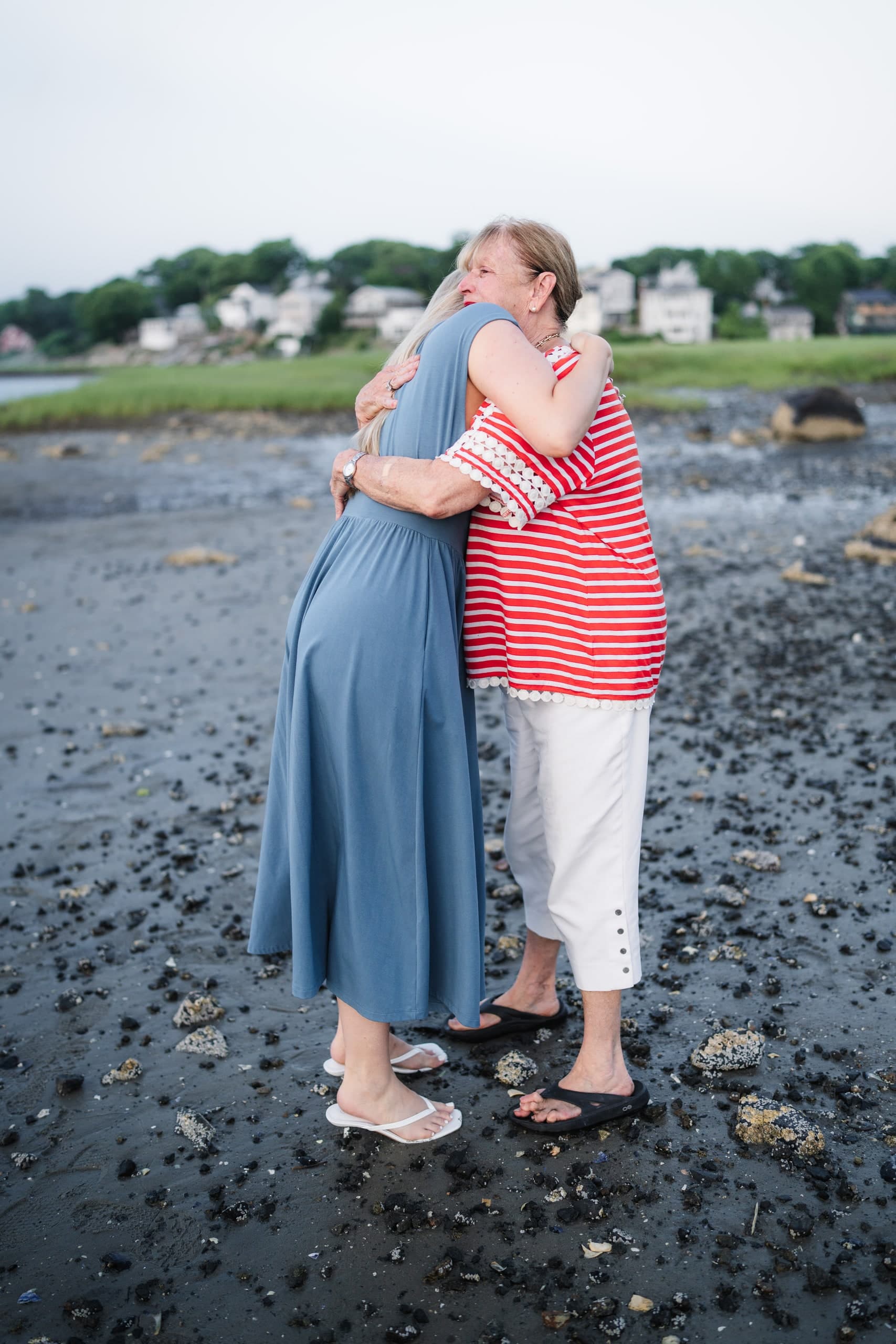 The newly engaged woman hugging an older family member, seen from behind her shoulder.