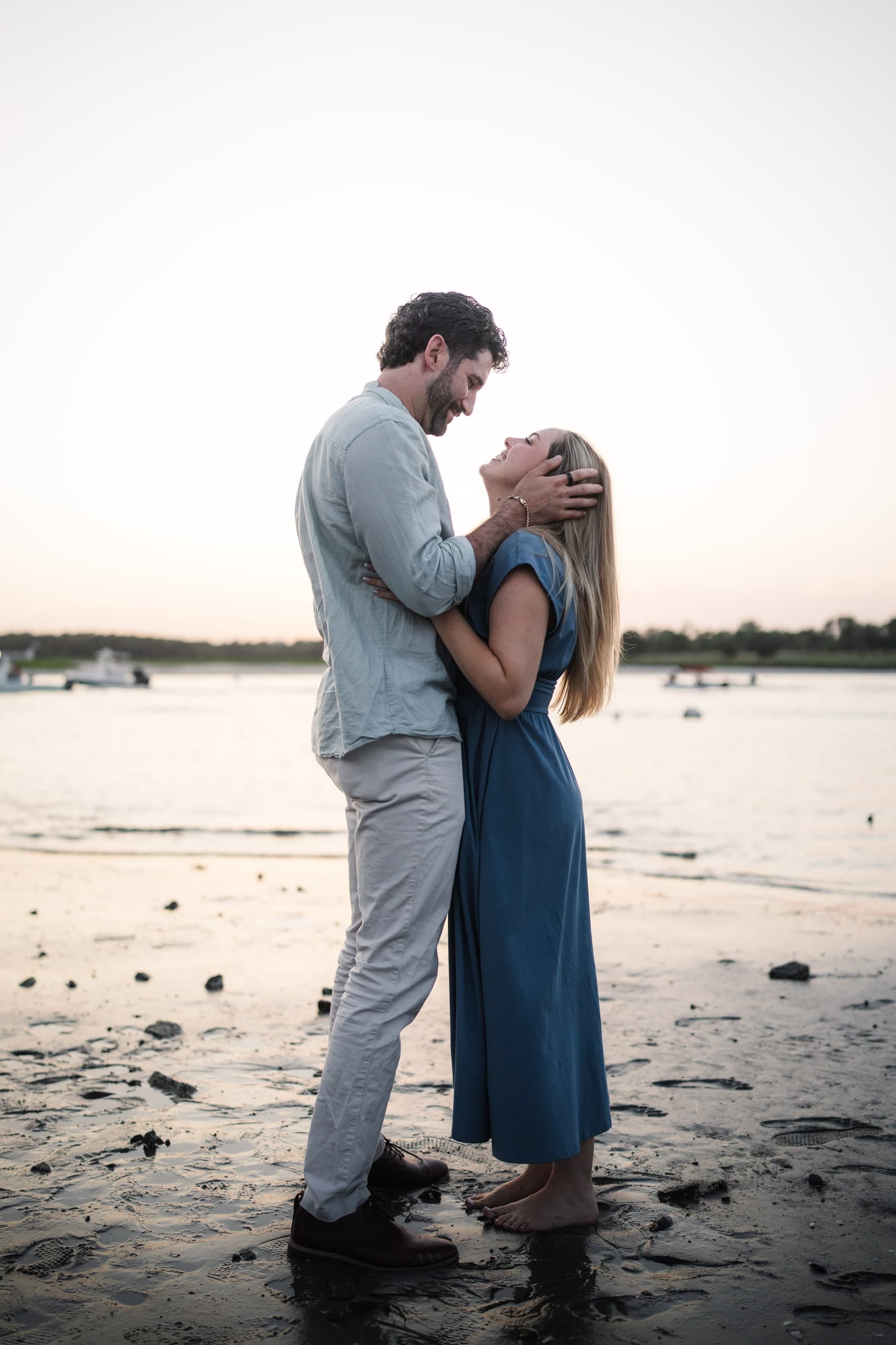 A couple standing forehead to forehead on the beach in the evening light.