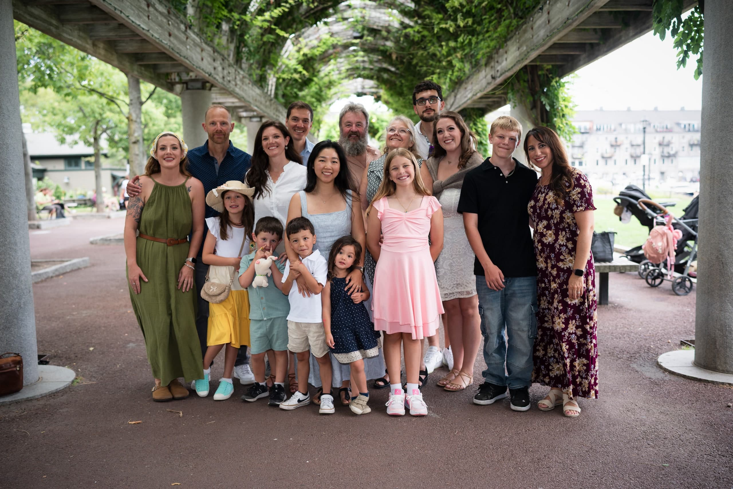 A large extended family gathered together beneath a wisteria-covered pergola.