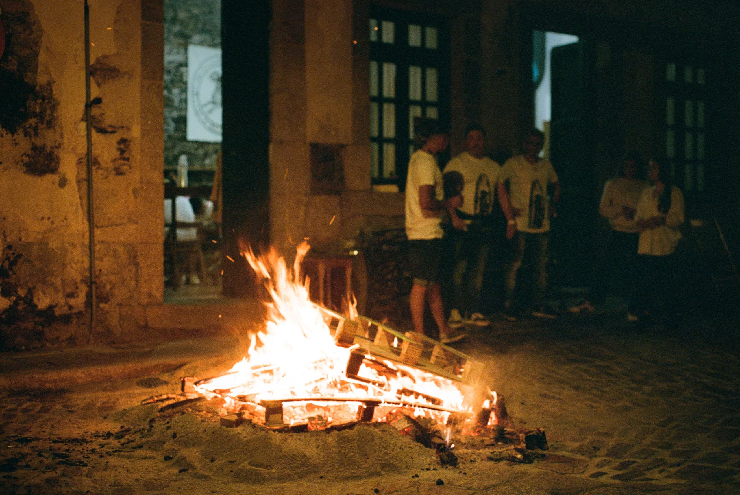 A group gathered around a bonfire at night.
