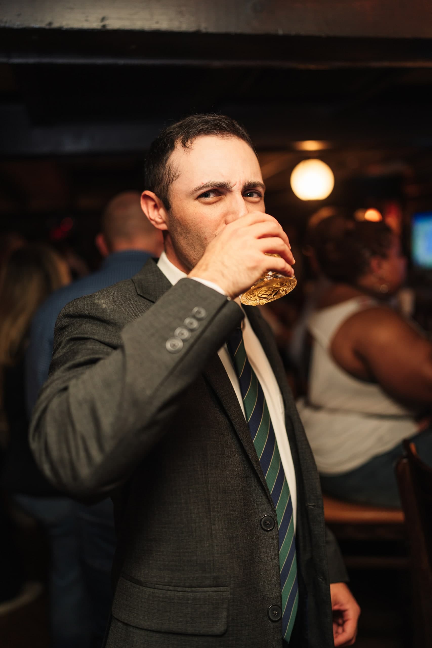 A guest mid-toast, drinking from a glass, caught candidly.