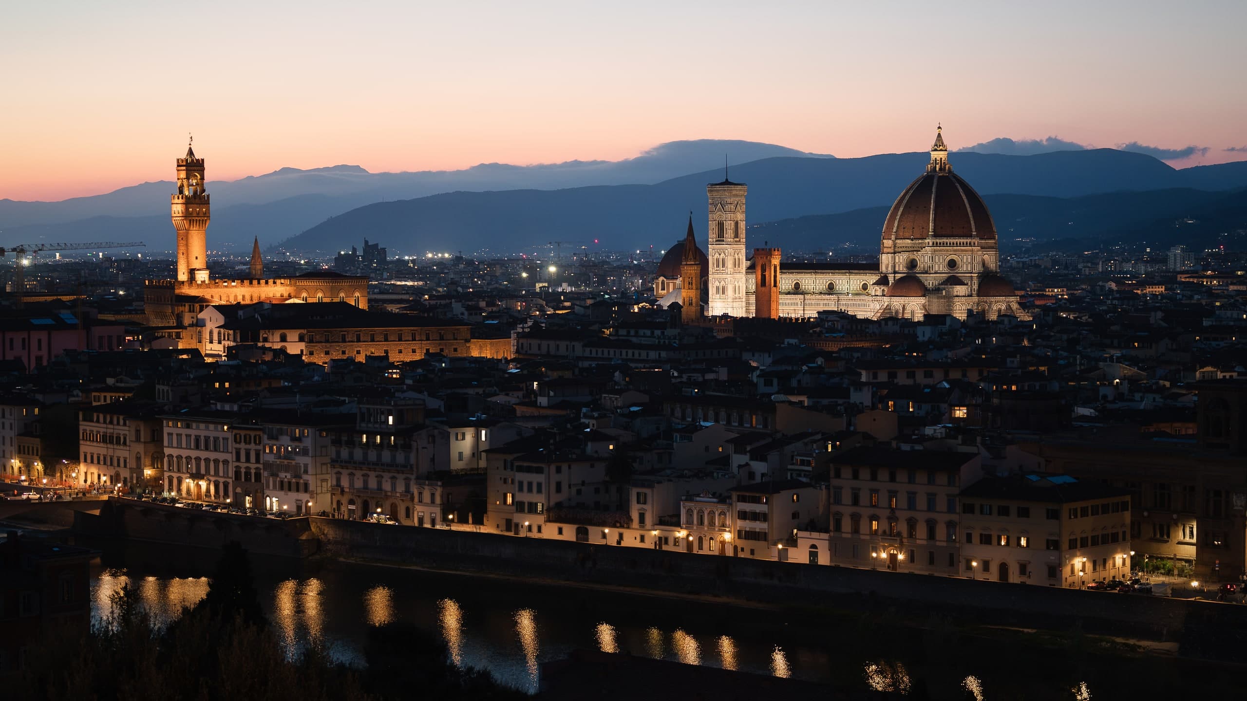 The Florence skyline at dusk, the Duomo lit above the rooftops.
