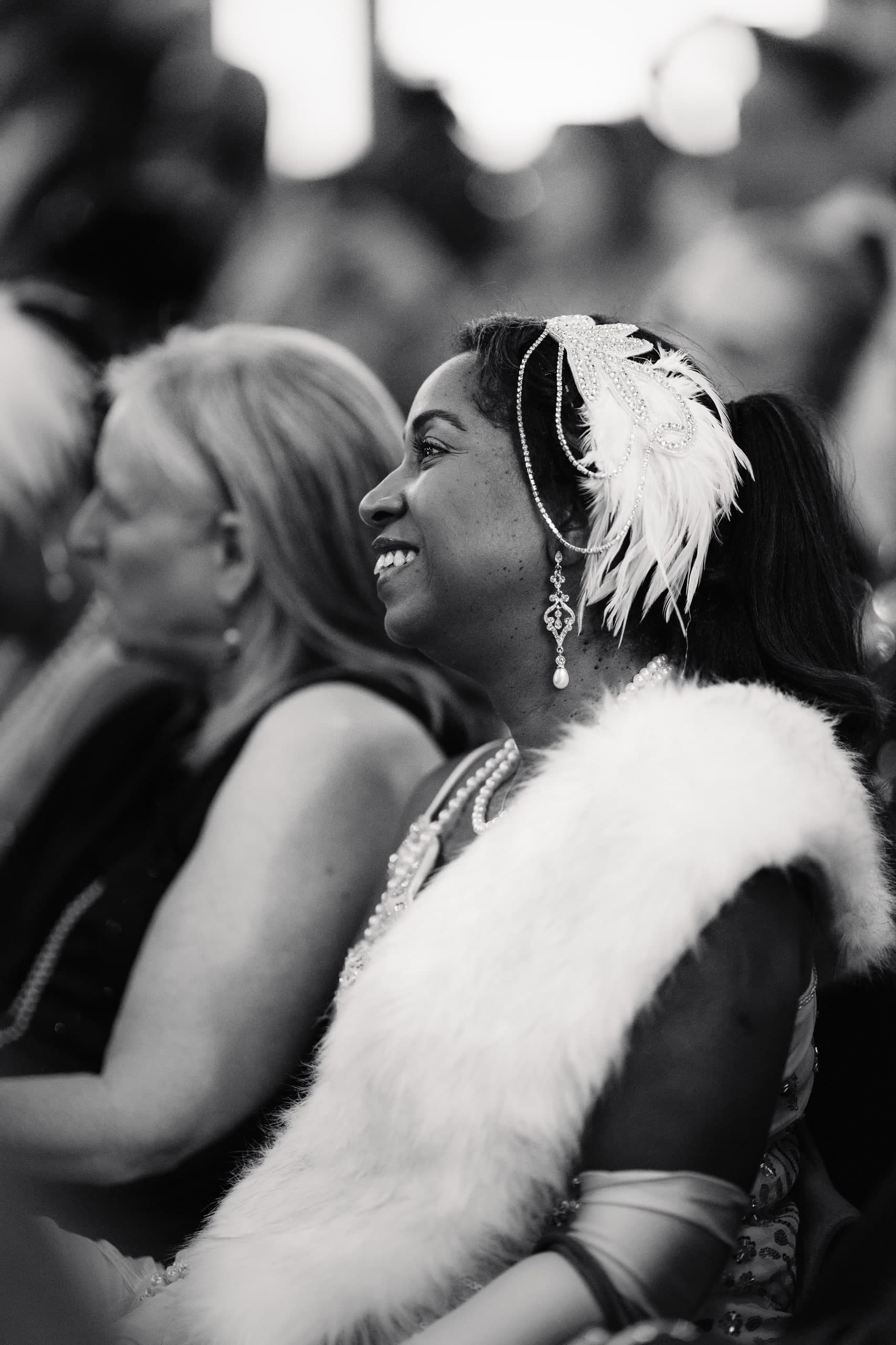 A black-and-white photo of two women embracing cheek to cheek, one wearing a feather boa.