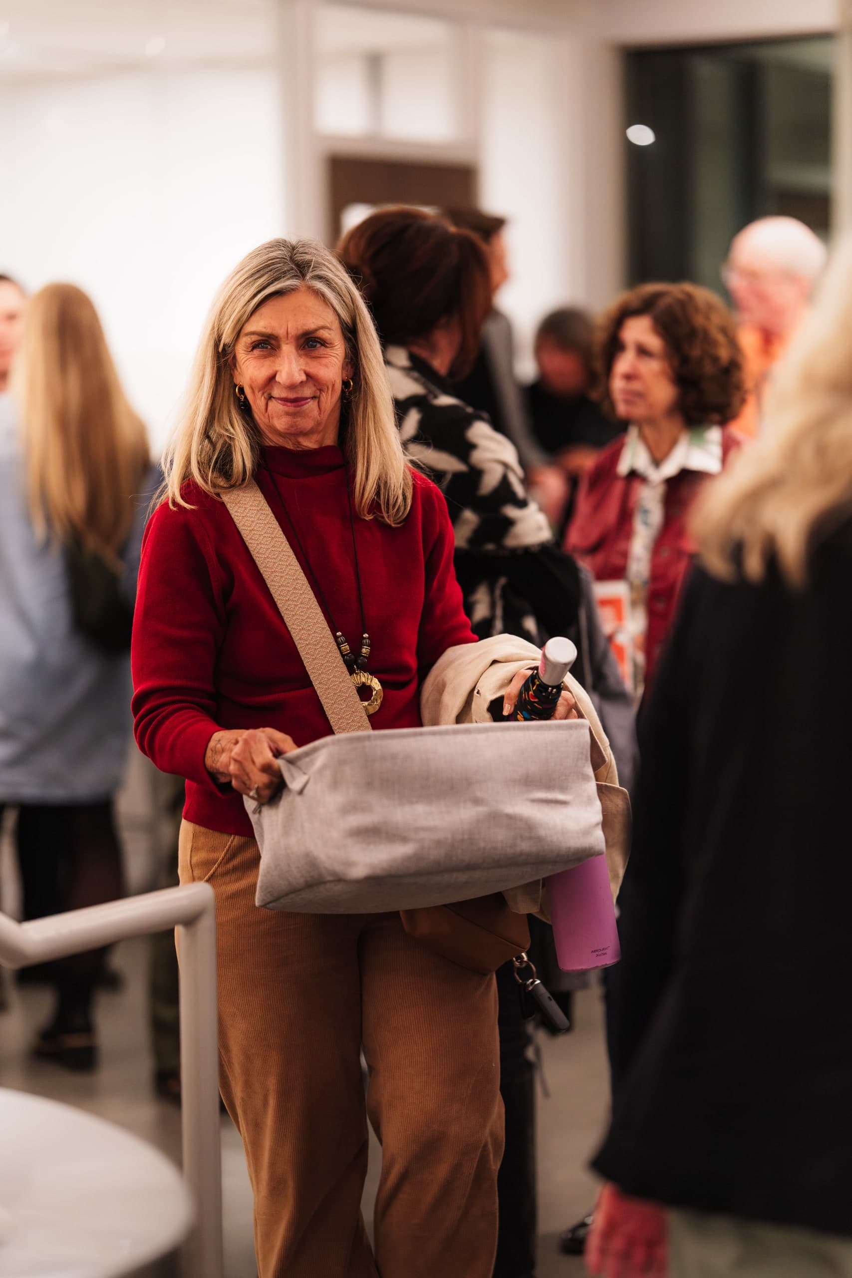 A woman in a red sweater mingling at an indoor reception.
