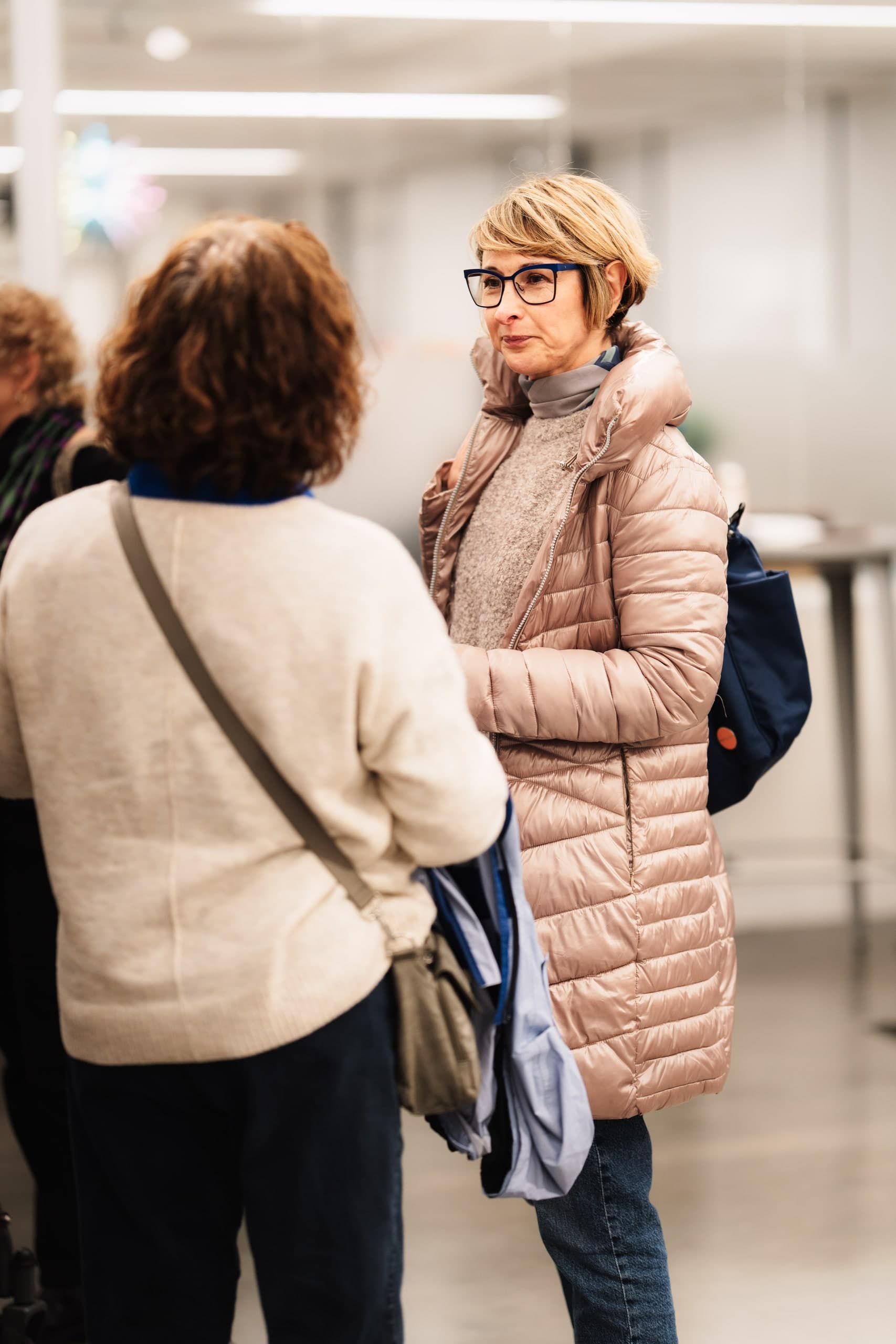 Two women in conversation at an indoor reception.
