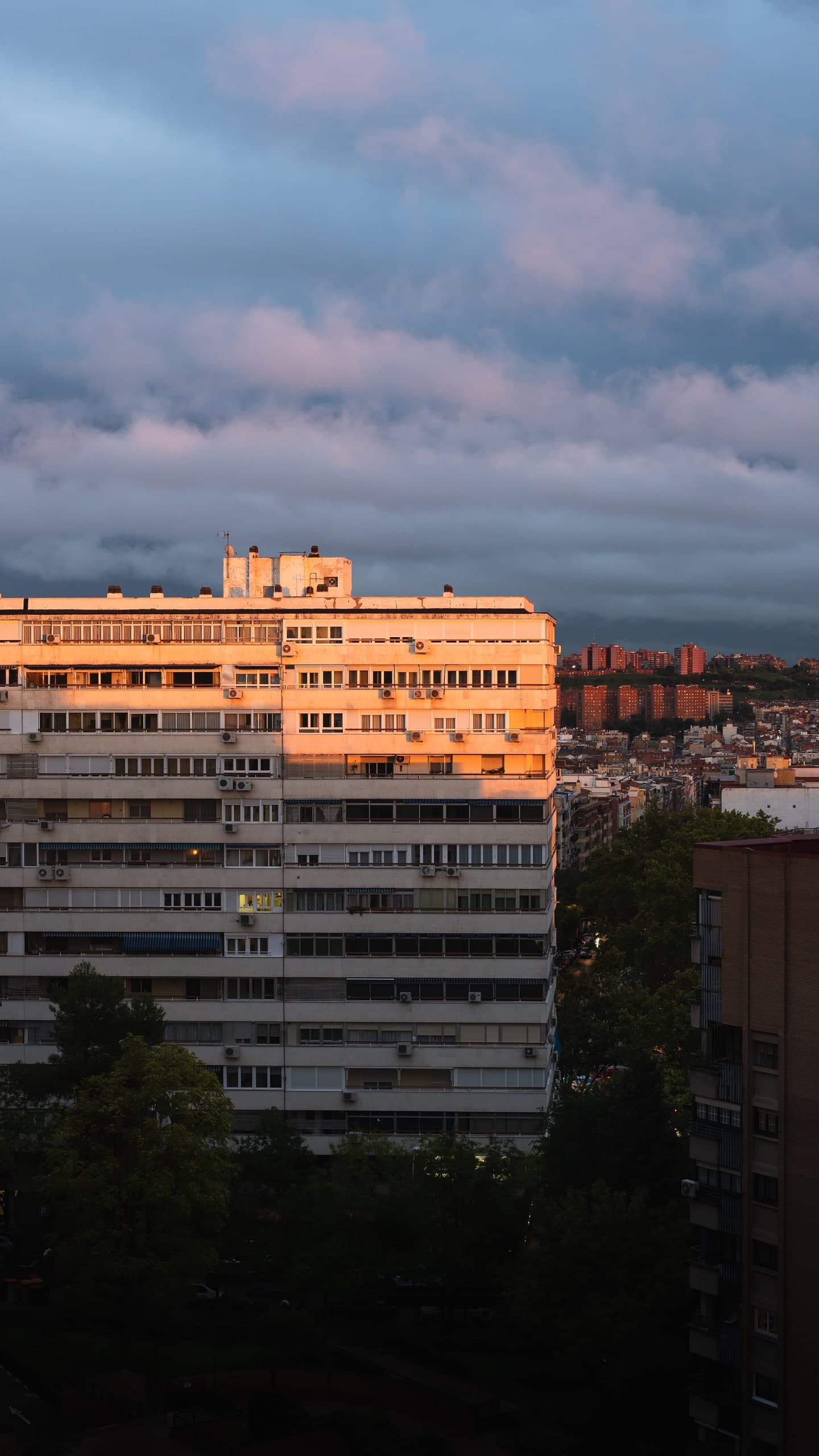 A Madrid apartment building lit gold at sunset, the city sprawling behind it.
