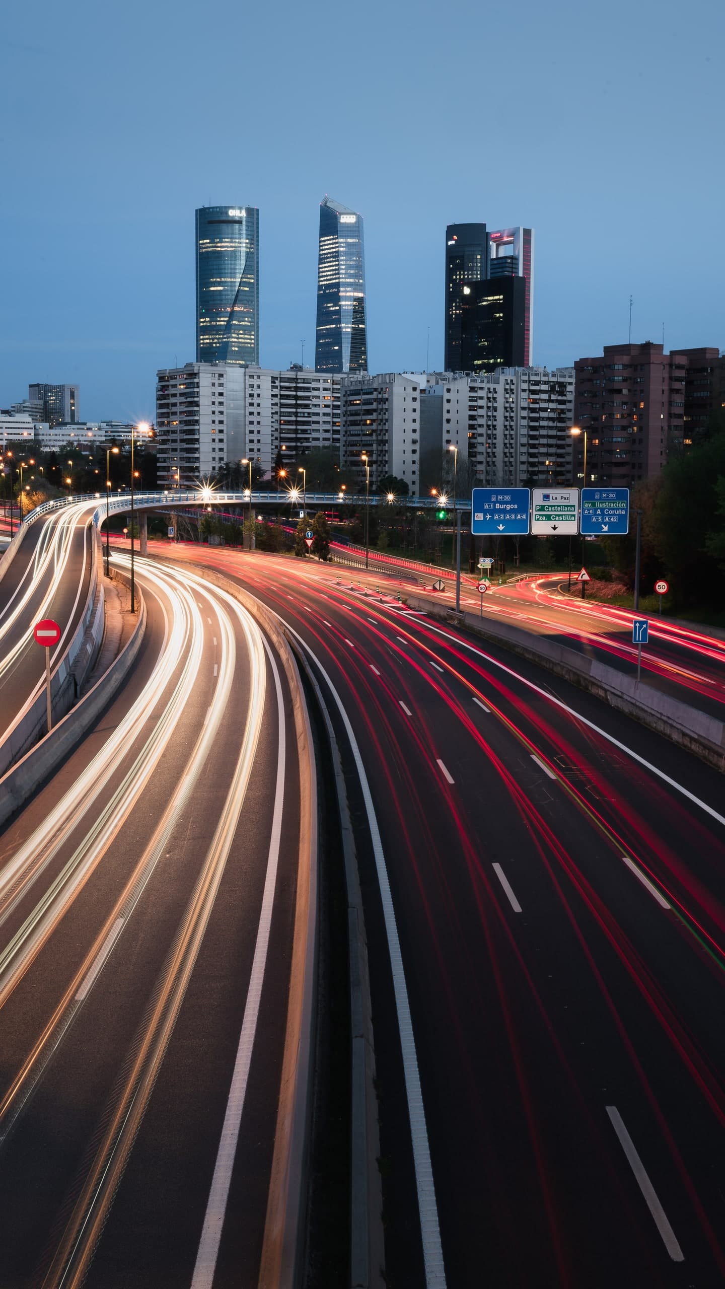 Light trails streaking along a Madrid highway at dusk.
