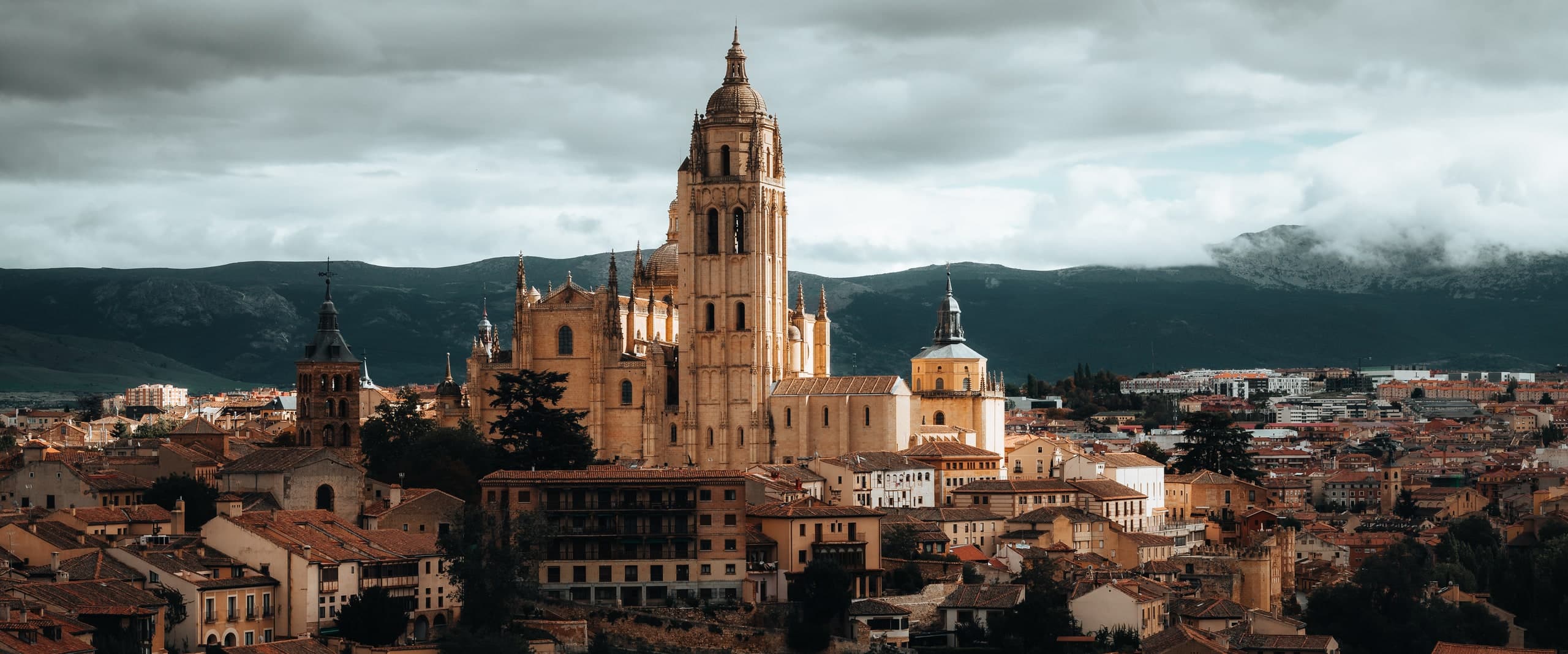 The cathedral of Segovia rising above the plaza under a cloudy sky.