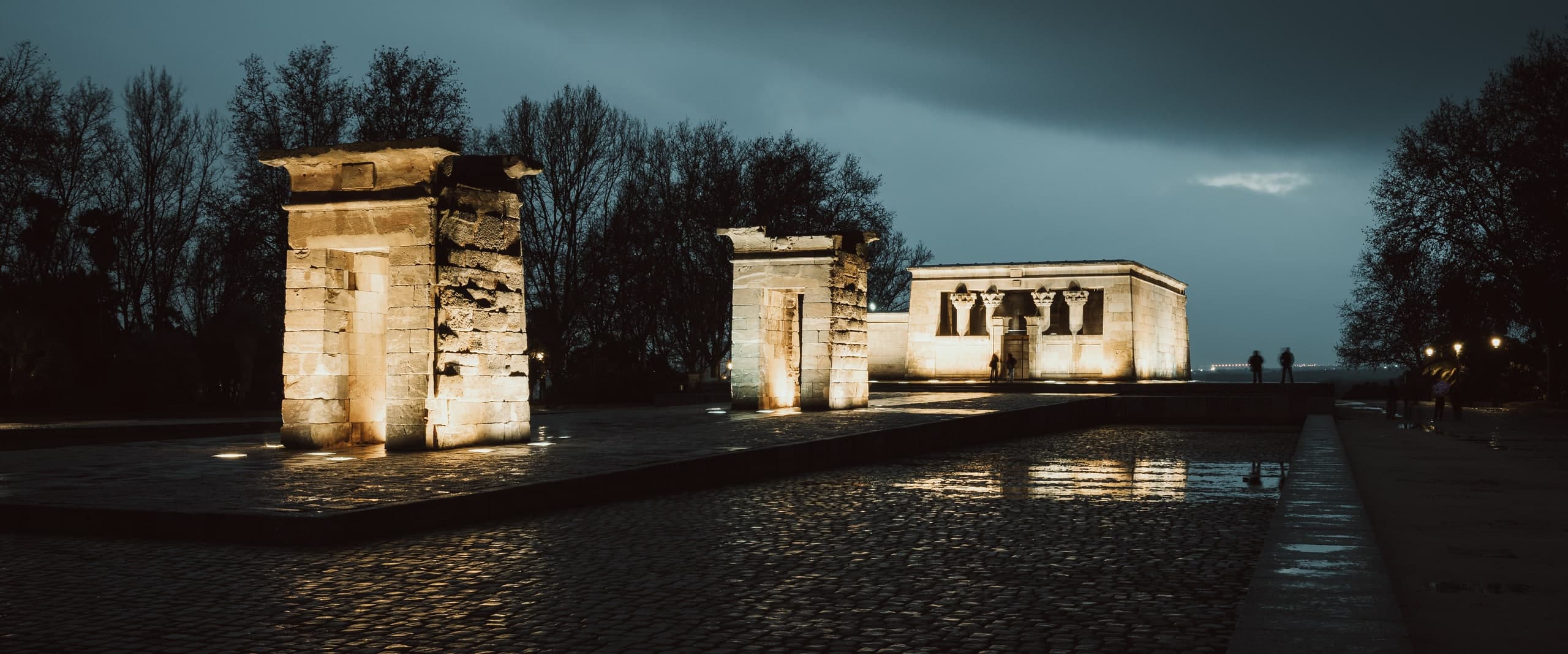 The Temple of Debod in Madrid lit at night, reflected in the surrounding pool.