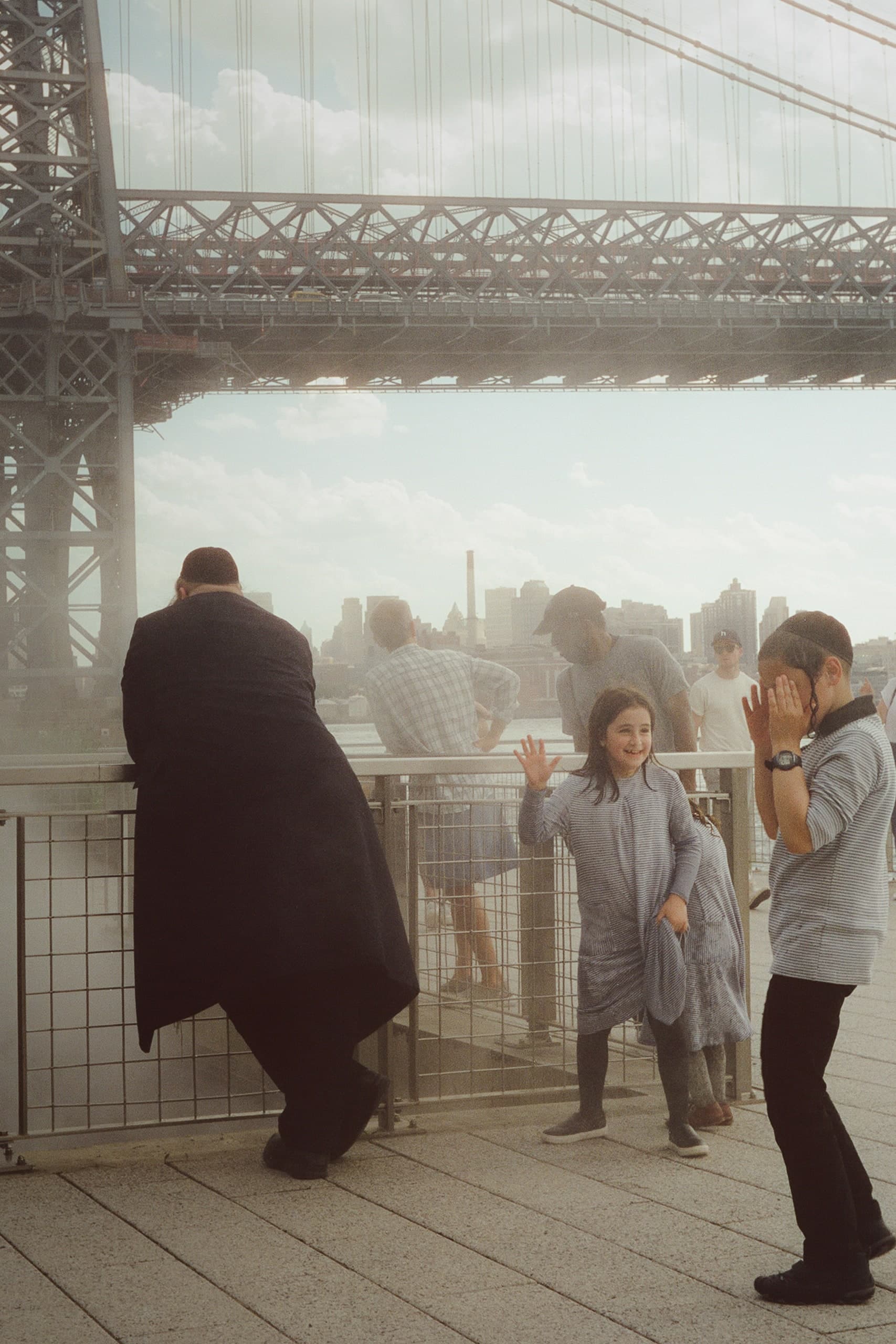 A family looking out from under the Williamsburg Bridge toward the Manhattan skyline.